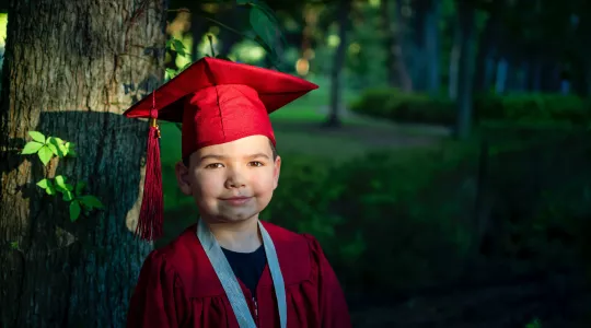 Young child in red high school gown